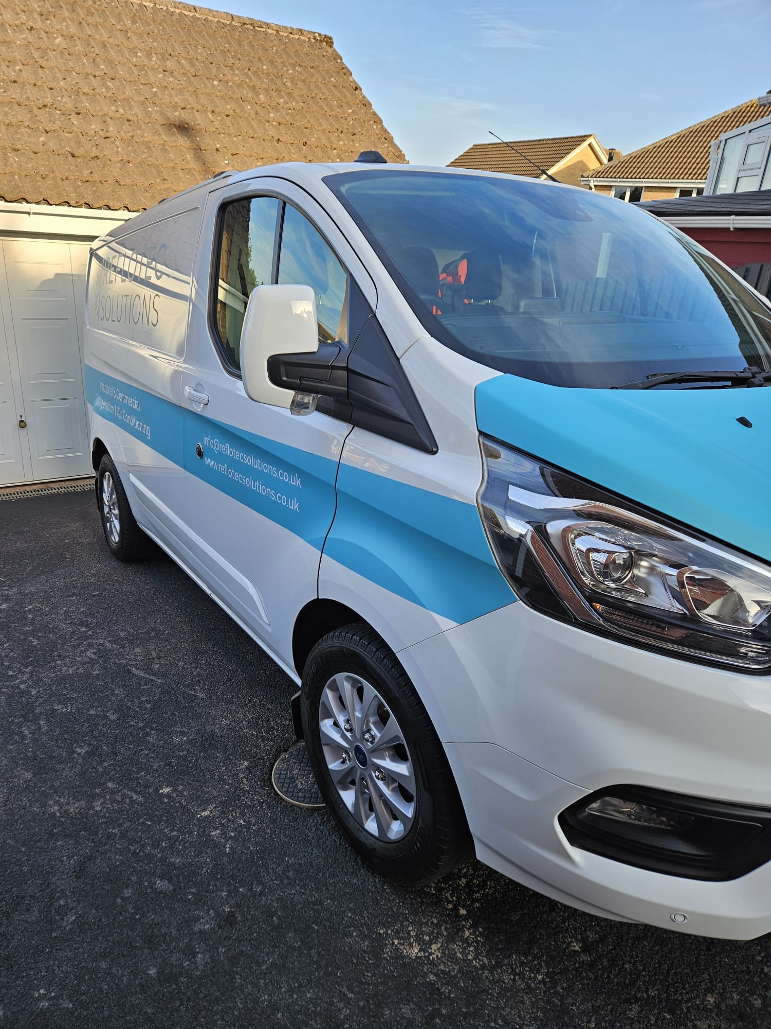 White and blue liveried Ford Transit Custom van cleaned on a driveway