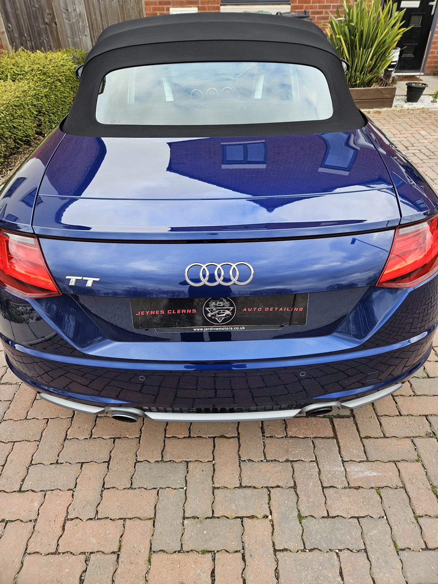 Rear of a blue Audi TT convertible with a freshly cleaned black fabric roof