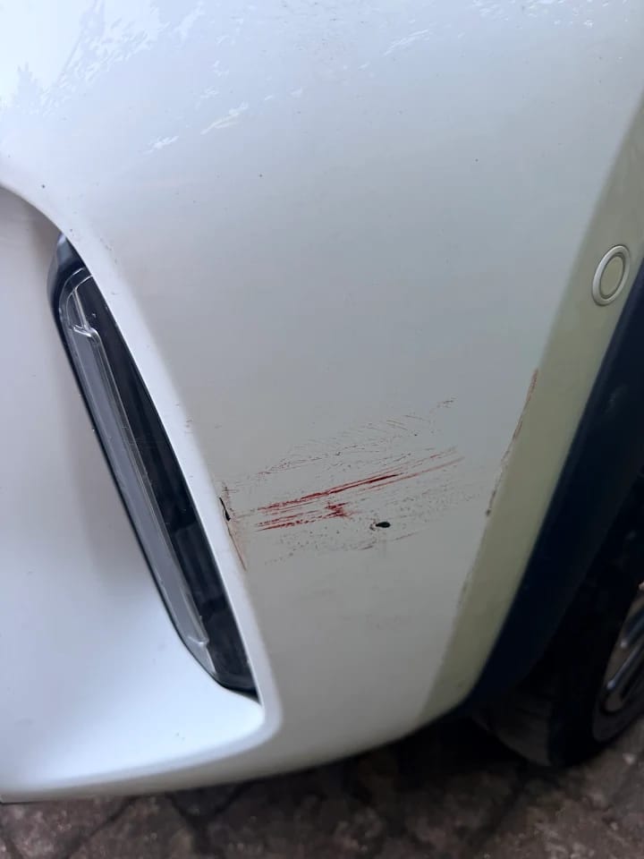 White vehicle panel with red surface marks before treatment